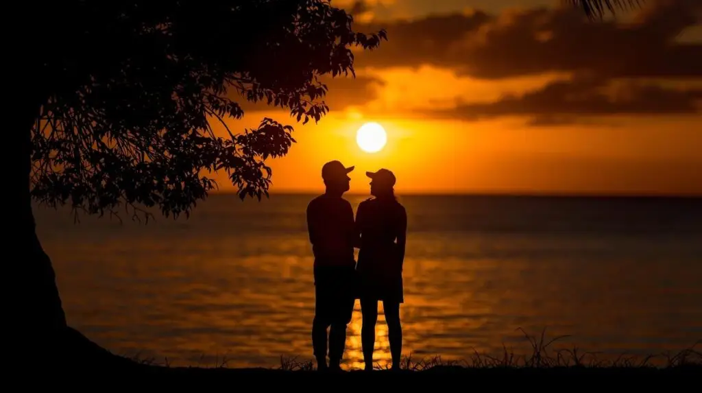 Una pareja disfruta de la puesta de sol en la playa. Un momento romántico con el cielo anaranjado y el océano.