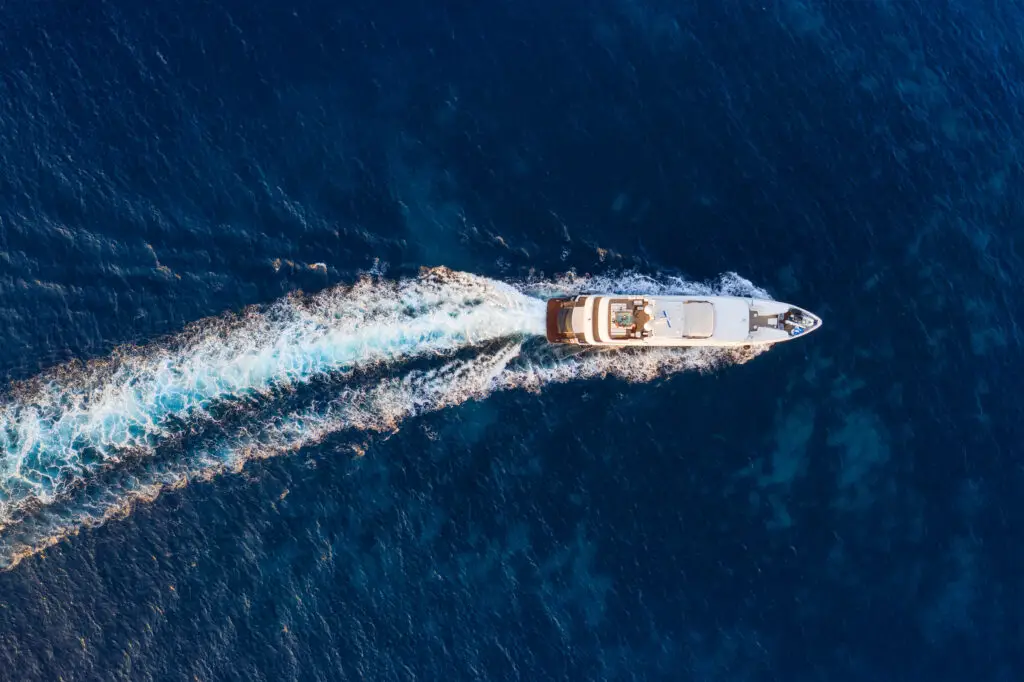 Luchtfoto van een cruiseschip varend door het helderblauwe water van Raja Ampat