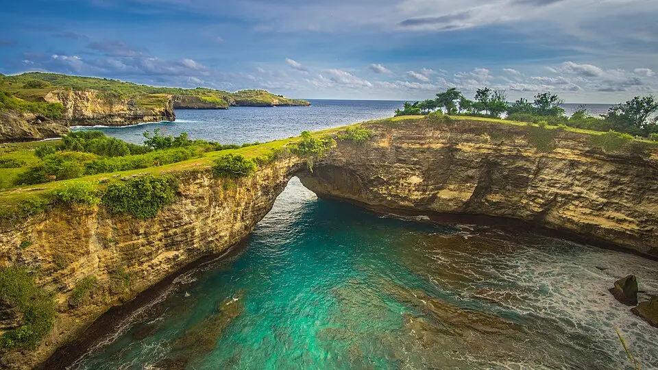 Un impresionante arco de roca natural sobre aguas turquesas en Nusa Penida, Bali.