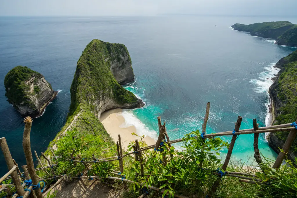Vista de una isla de acantilados verdes en la remota costa de Nusa Penida, destino ecoturístico de Indonesia.