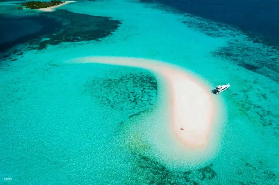 Luchtfoto van Pink Beach, Komodo National Park, met boten en toeristen op de zandbank.