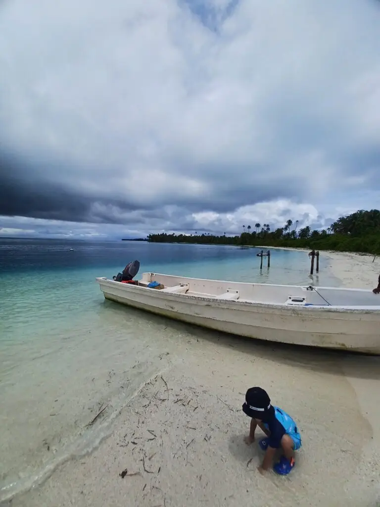 Children play on the white sand beach of Pulau Banyak Aceh Singkil near the boat, a hidden paradise.