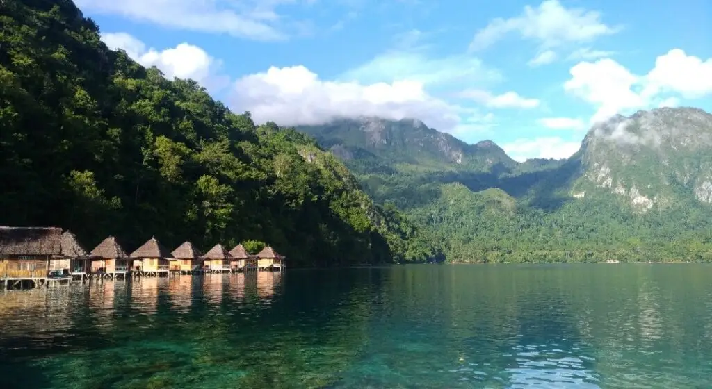 De overwaterbungalows van Ora Beach, Maluku, liggen in een rustige baai omringd door weelderig groene bergen.