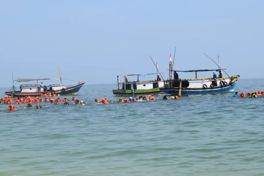Buceadores practican snorkel con chalecos salvavidas cerca de un barco en Gili Ketapang, Probolinggo.