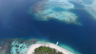 Pantai tropis dengan air jernih dan terumbu karang, terlihat dari atas keindahan pulau kecil di Indonesia. Pulau banyak