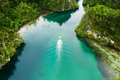 Boottocht door turquoise wateren omgeven door weelderig groen in Raja Ampat