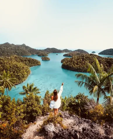 Een vrouw kijkt naar de prachtige Raja Ampat eilanden, hun turquoise water en weelderig groene bomen.